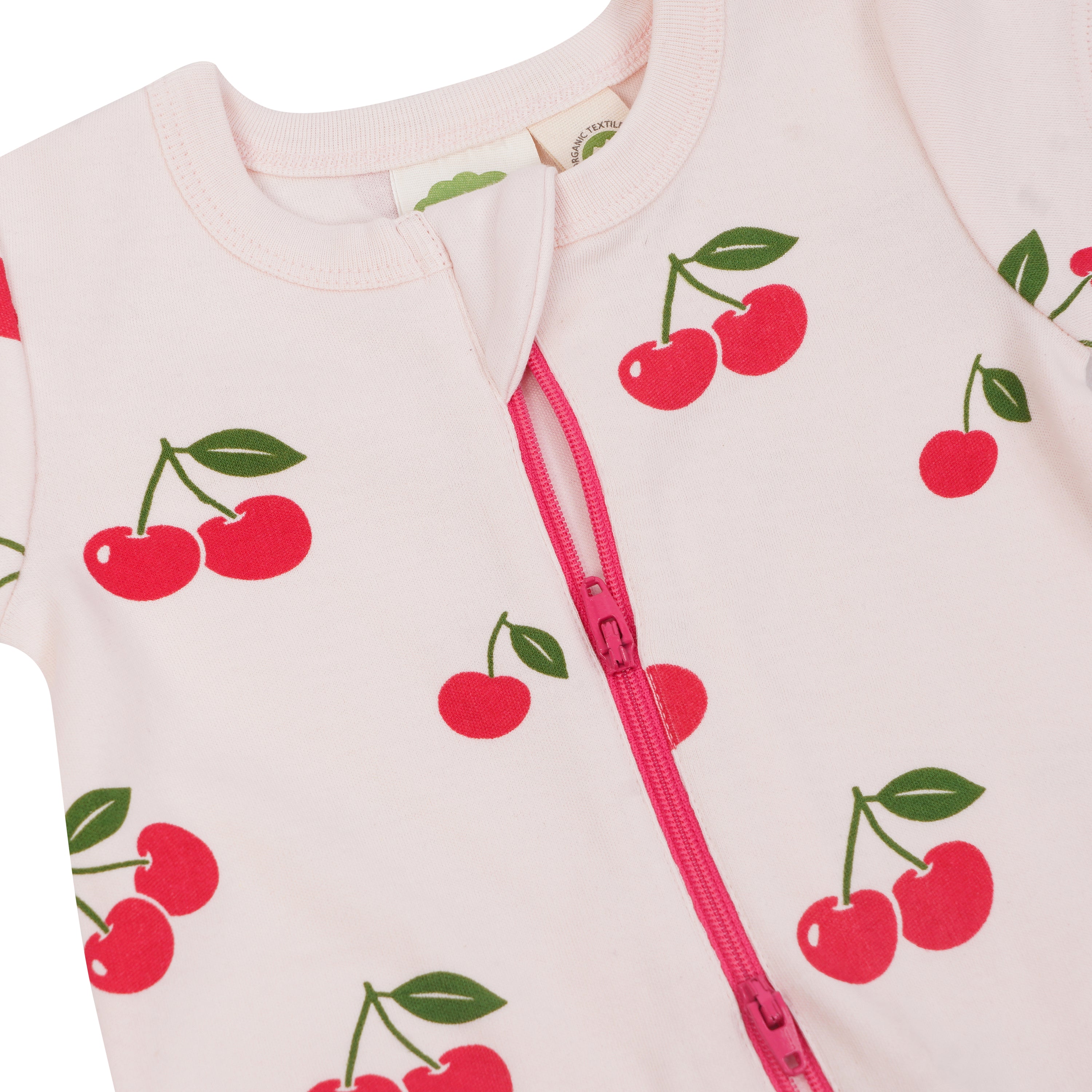 Baby onesie with cherry pattern and pink zipper on a light pink background